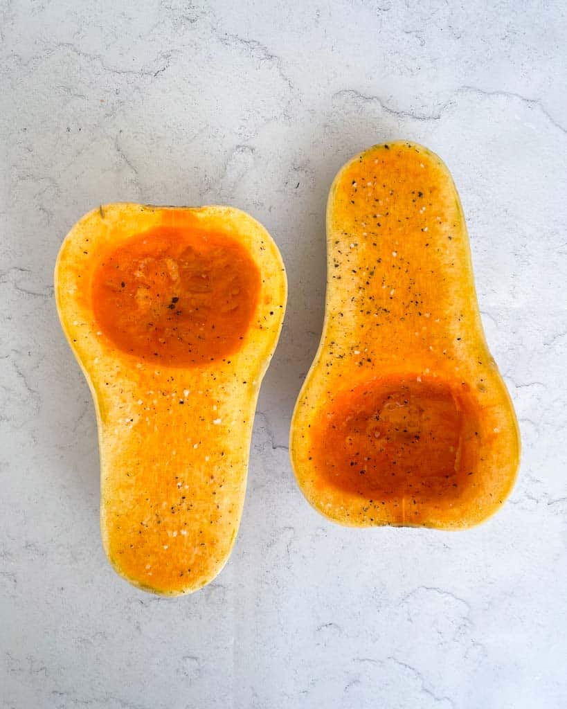 two halves of butternut squash with salt and pepper