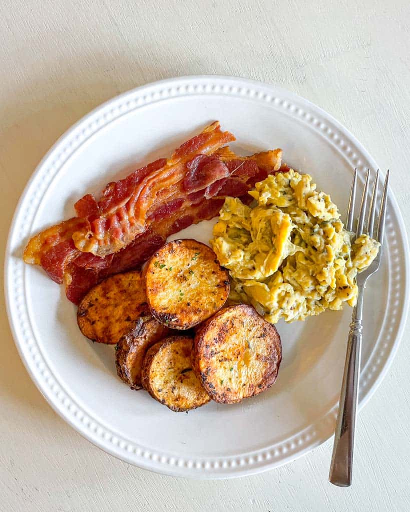 cottage fries on a plate with scrambled eggs and bacon