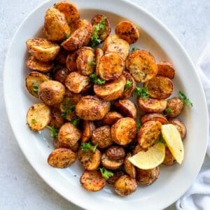air fried potatoes on a white plate with two lemon wedges
