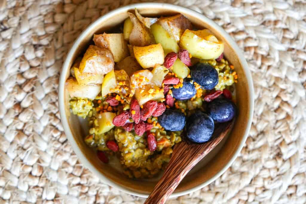 golden turmeric oatmeal in a small bowl with toppings and a spoon