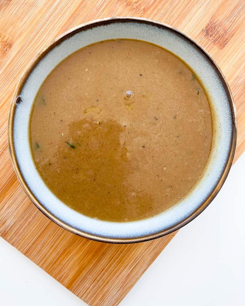 gluten free gravy made from scratch in a white bowl on top of a wooden board