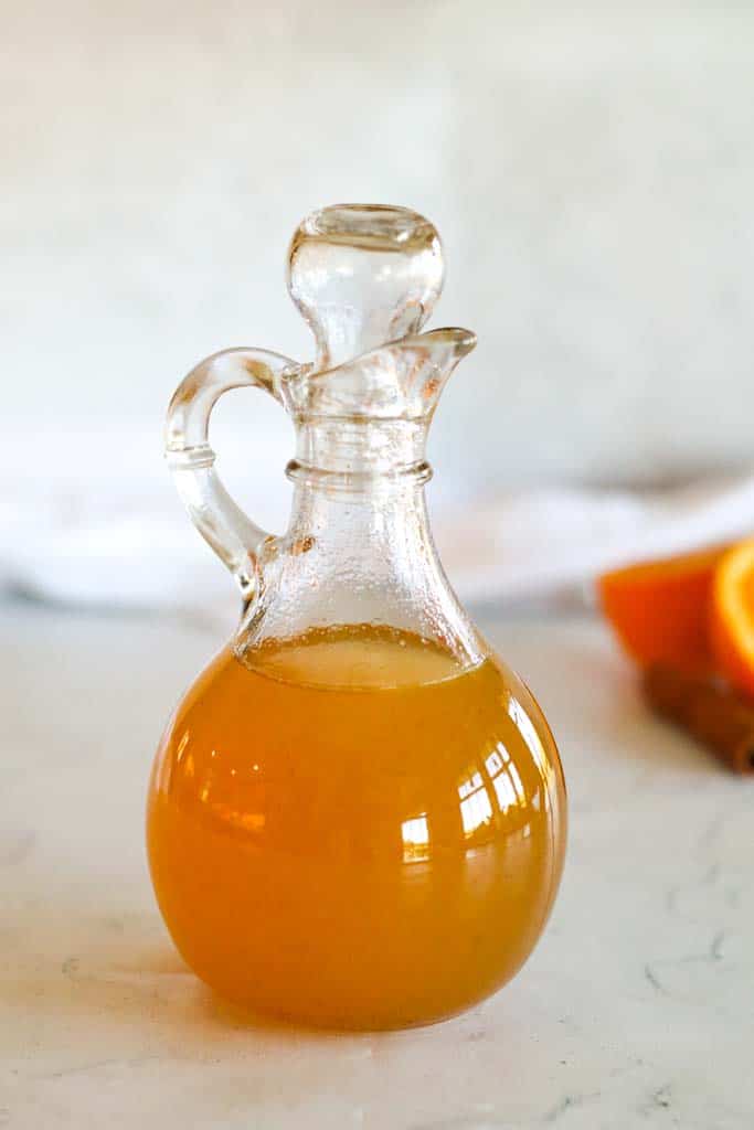 orange simple syrup in a glass bottle