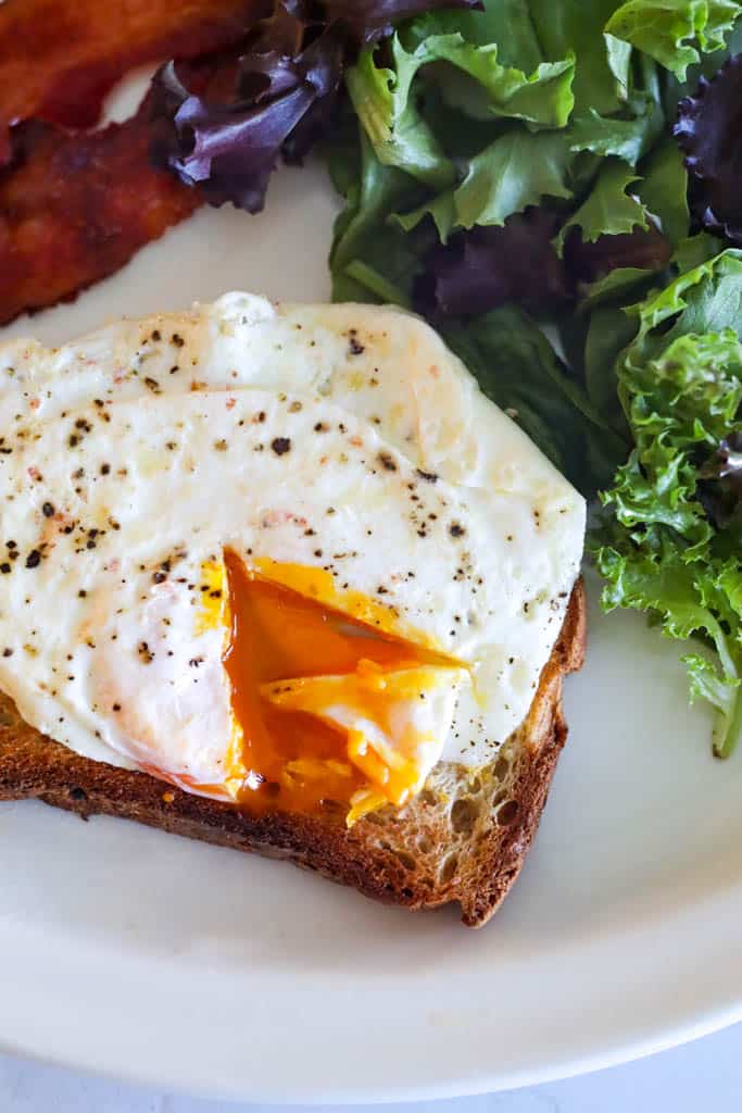 close up of an over medium egg with toast