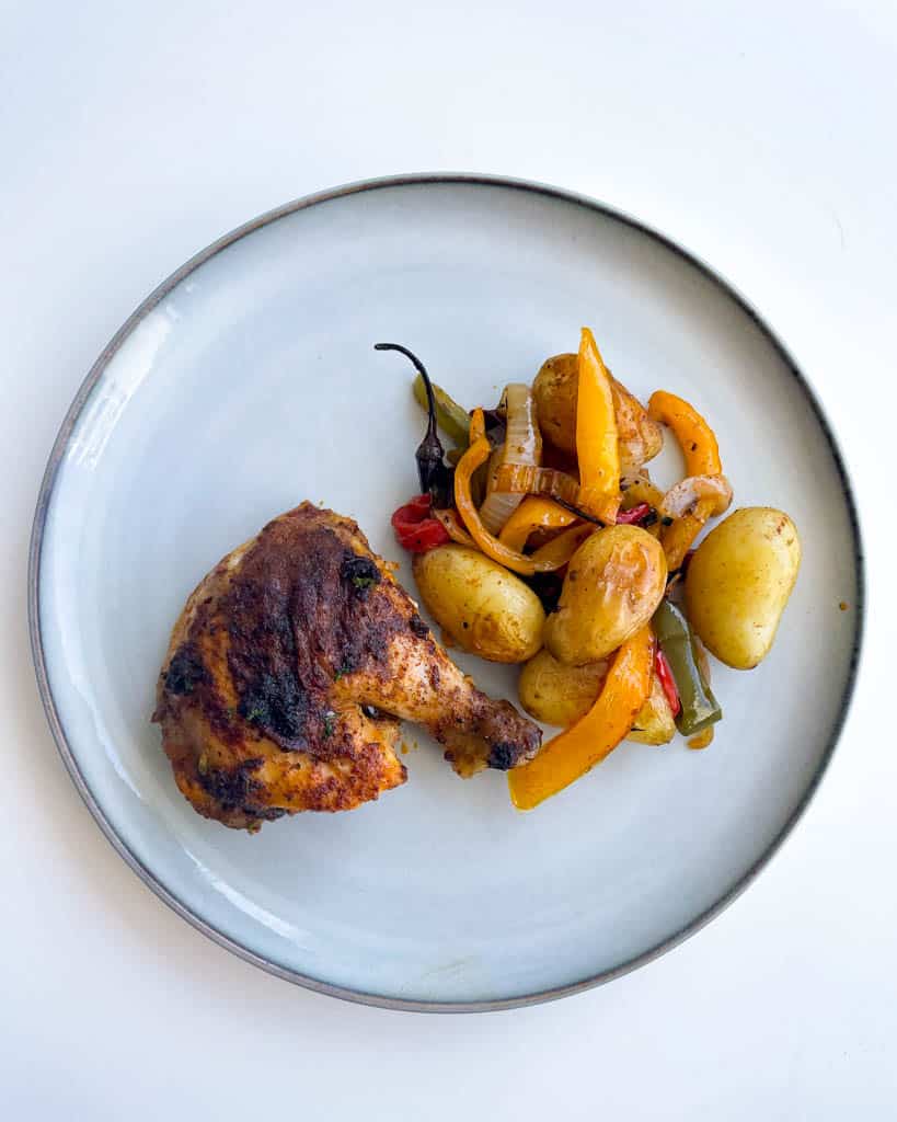 overhead view of plated chicken thigh with roasted potatoes and veggies
