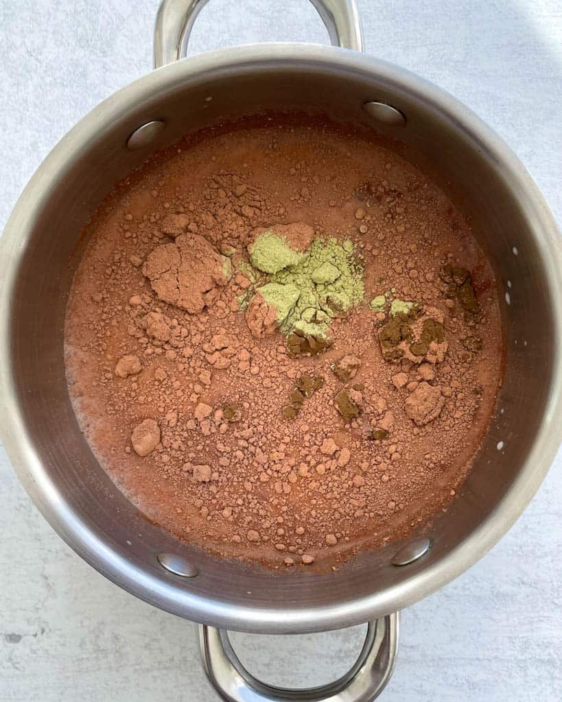 cacao, chaga powder, ashwagndha in saucepan with oat milk to make hot chocolate