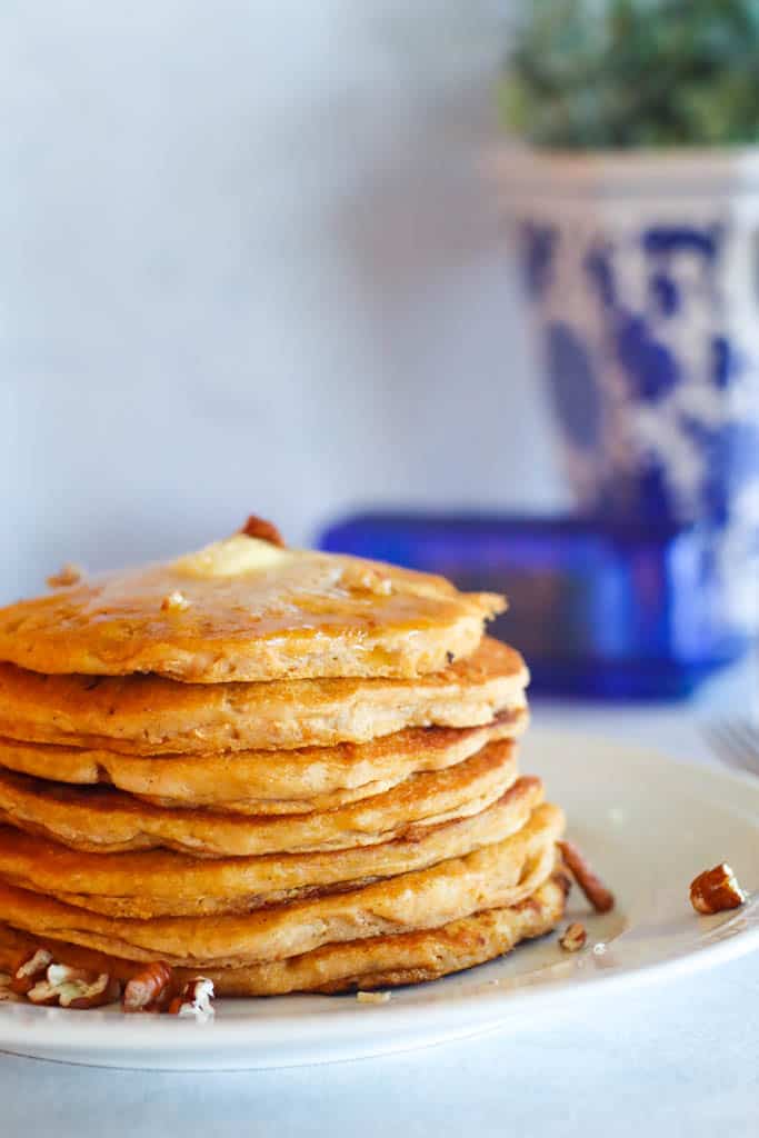 stack of sweet potato pancakes topped with butter and chopped pecans