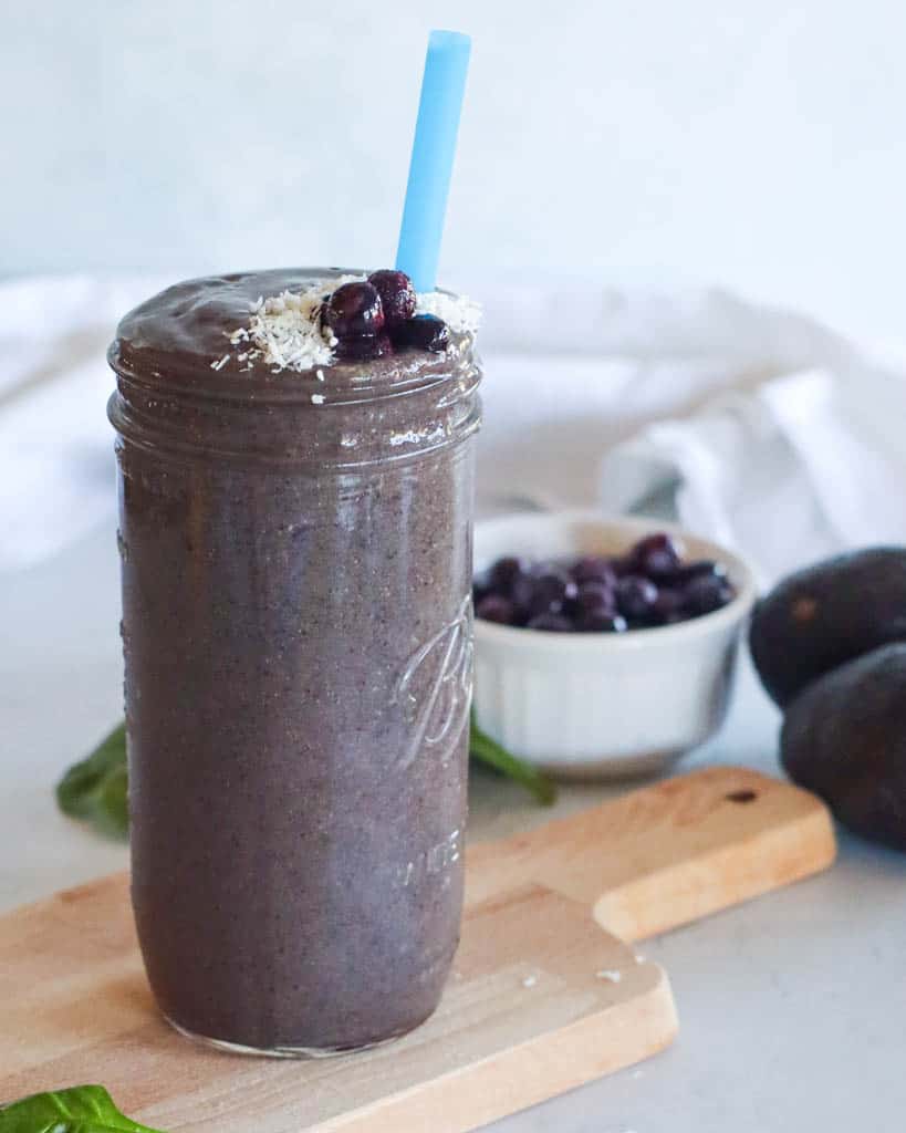 smoothie in a mason jar with a small bowl of blueberries in the background