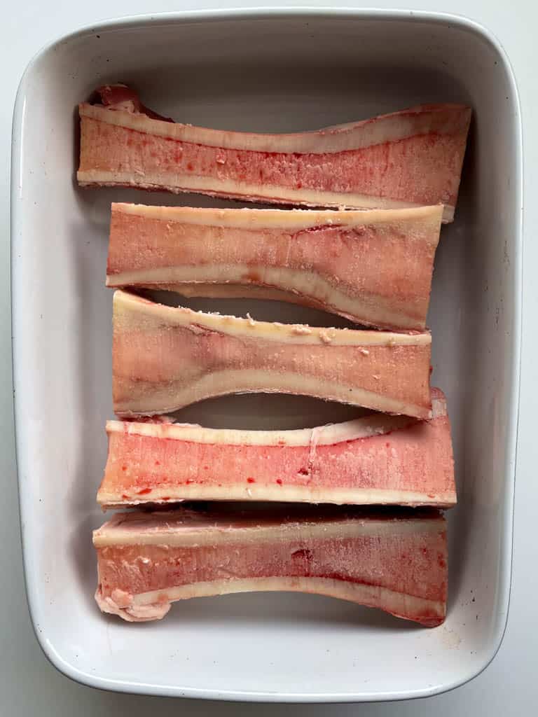 beef bone marrow bones cut lengthwise and placed in a baking dish for roasting