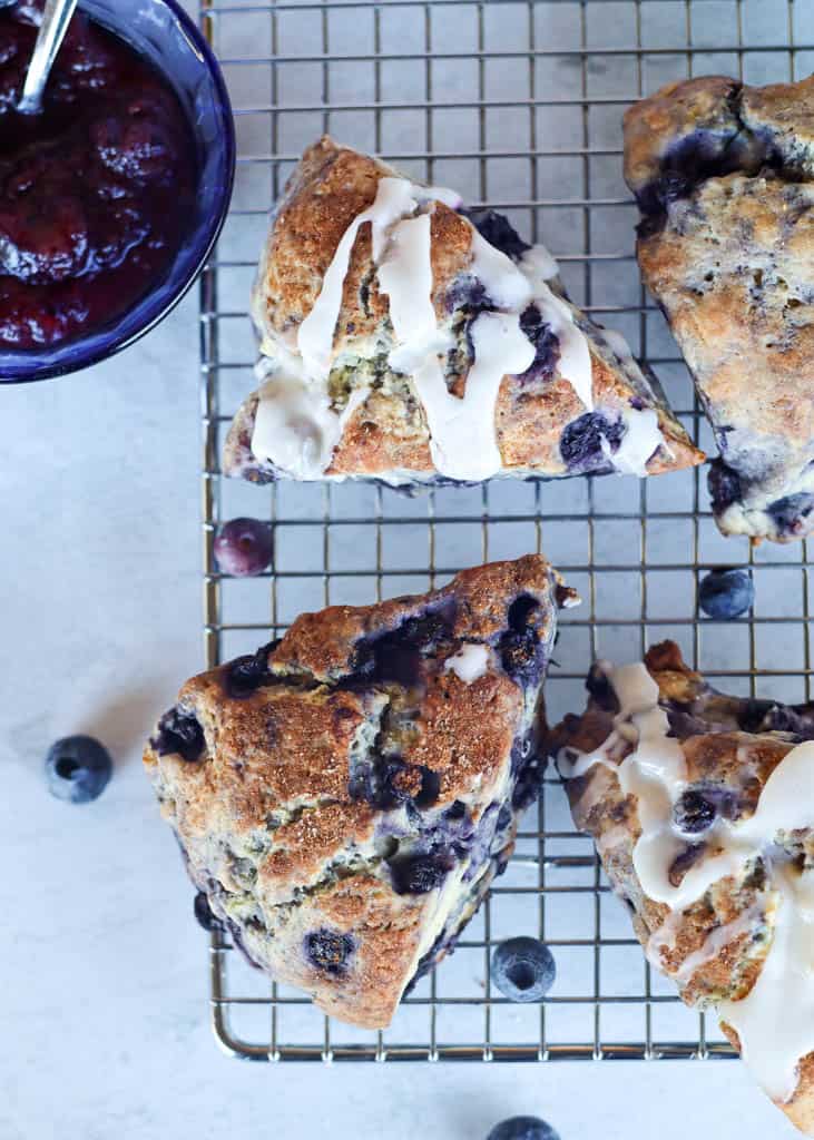 overhead view of unglazed and glazed gluten-free blueberry scones on a rack