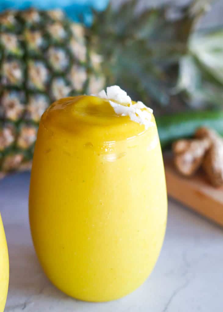 glass full of mango pineapple smoothie garnished with coconut