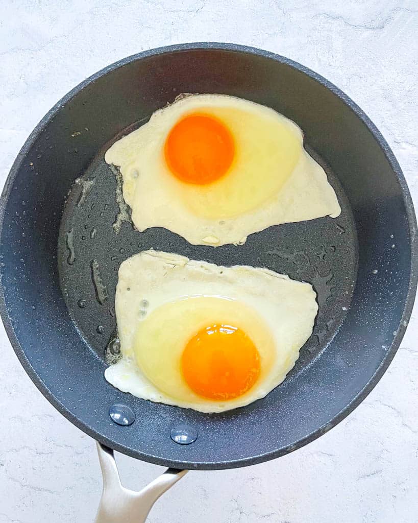 eggs frying in a non-stick pan before they are flipped