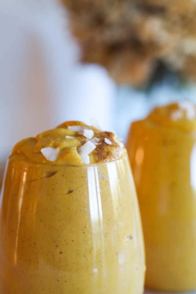close up of two orange smoothies in a glass