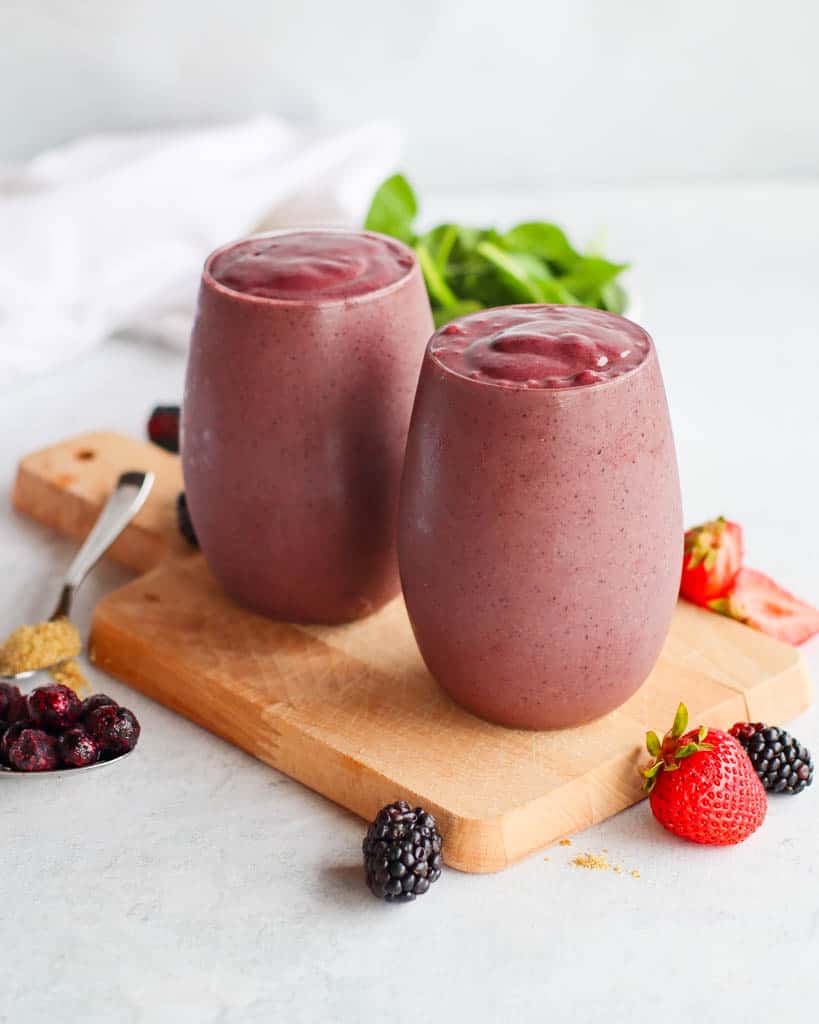 two glasses full of antioxidant smoothies with berries scattered around