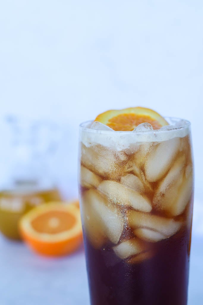 close up view of a glass full of cold brew tonic garnished with an orange slice