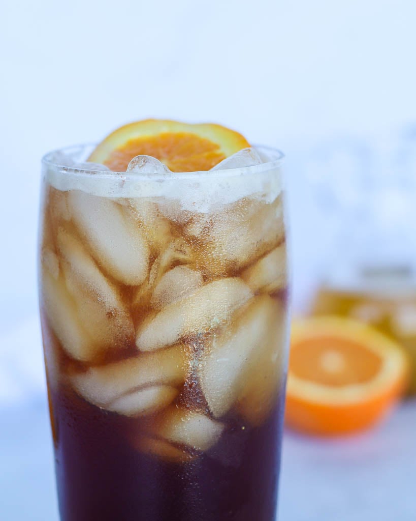 close up view of a glass full of cold brew tonic garnished with an orange slice