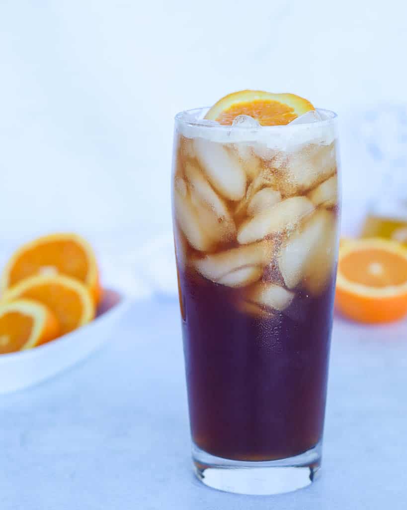 a glass full of cold brew tonic garnished with an orange slice