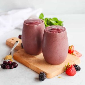 two glasses full of antioxidant smoothies with berries scattered around