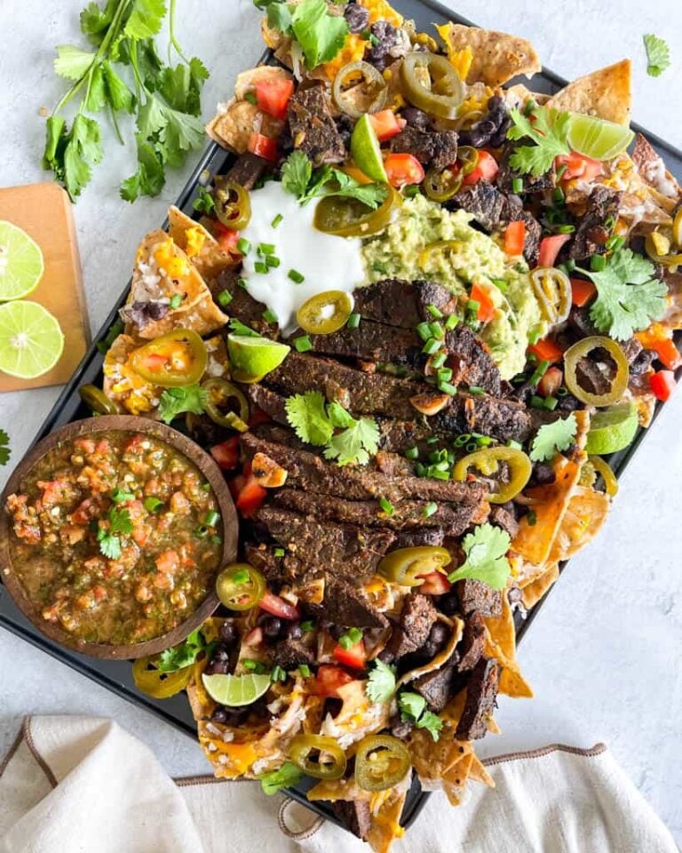 loaded carne asada nachos with beans, cheese, cilantro, guacamole, sliced jalapenos, with salsa served on the side