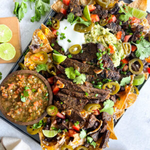 loaded carne asada nachos with beans, cheese, cilantro, guacamole, sliced jalapenos, with salsa served on the side