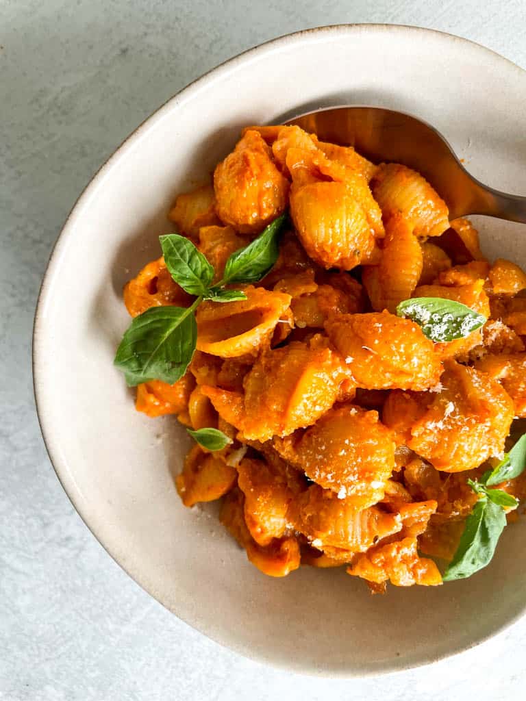 bowl of spicy vodka pasta topped with fresh basil