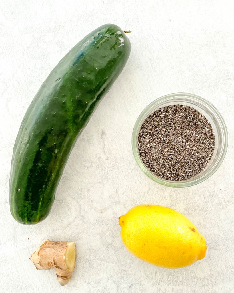 overhead view of a cucumber, ginger root, a lemon, and a small bowl of chia seeds