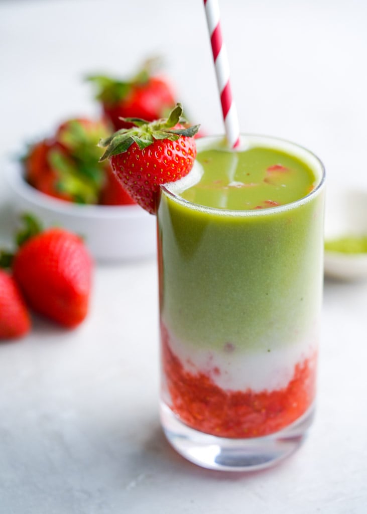 glass of strawberry matcha latte with strawberries in the background