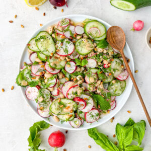 a platter full of cucumber radish salad with a spoon