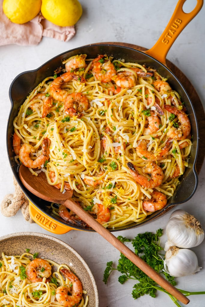 overhead view of pan full of lemon garlic pasta with shrimp with a wooden spoon inserted