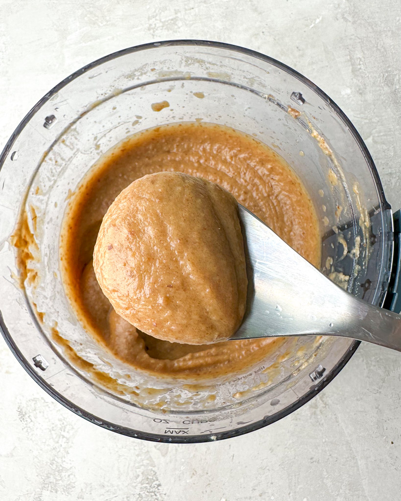 a spoonful of date caramel sauce over a blender containing more