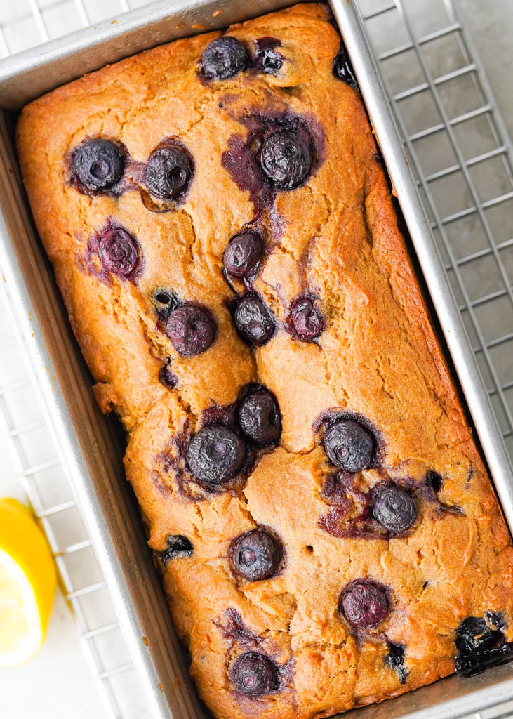 blueberry lemon bread in a loaf tin on a wire rack