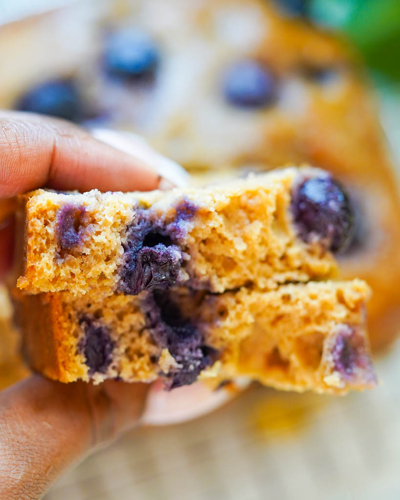 two pieces of blueberry lemon bread being held close to the camera to show texture