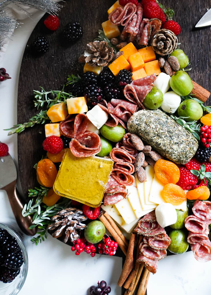 a charcuterie board filled with meats and cheeses shaped like a christmas tree with ornaments at the top of the tree and around the christmas charcuterie board tree