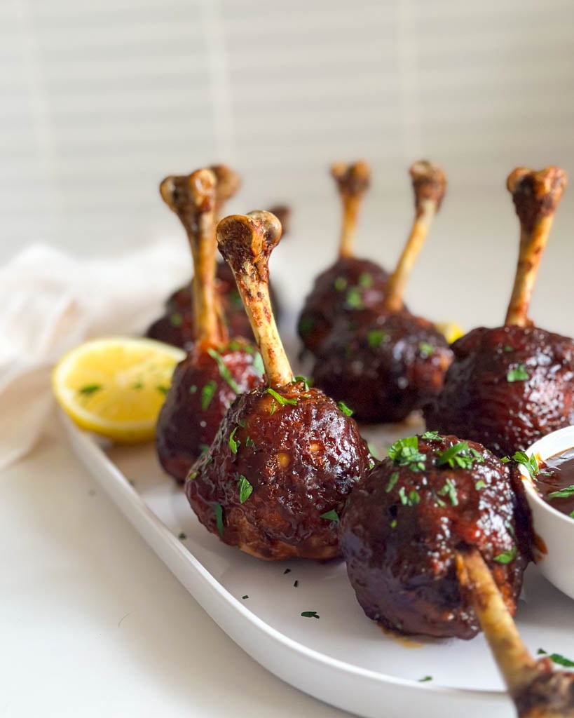barbecue chicken lollipop drumsticks on a plate with a wedge of lemon