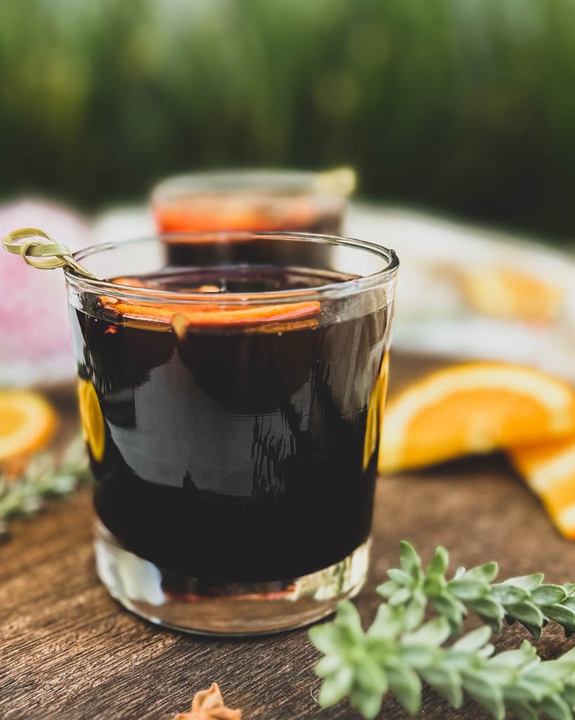 a close up of a glass of spiced wine with an orange slice on top