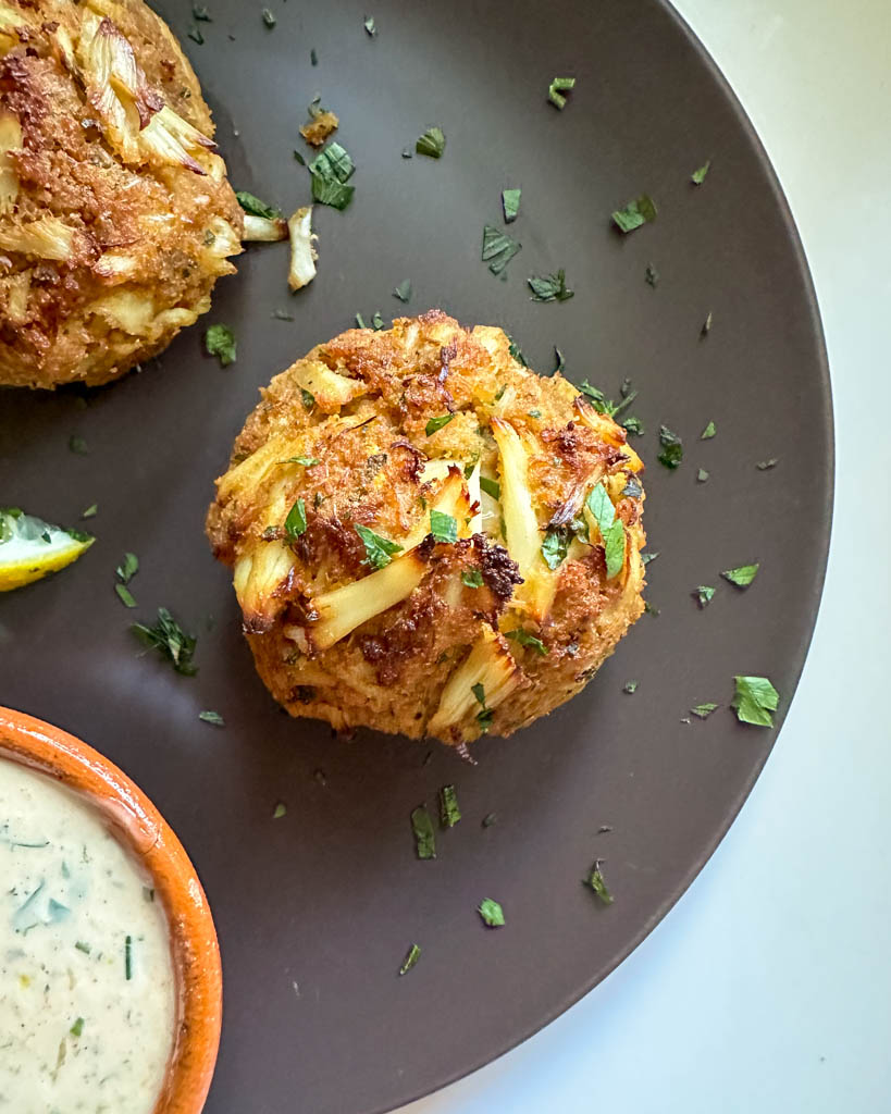 plated Maryland crab cakes with a partial view of aioli dipping sauce