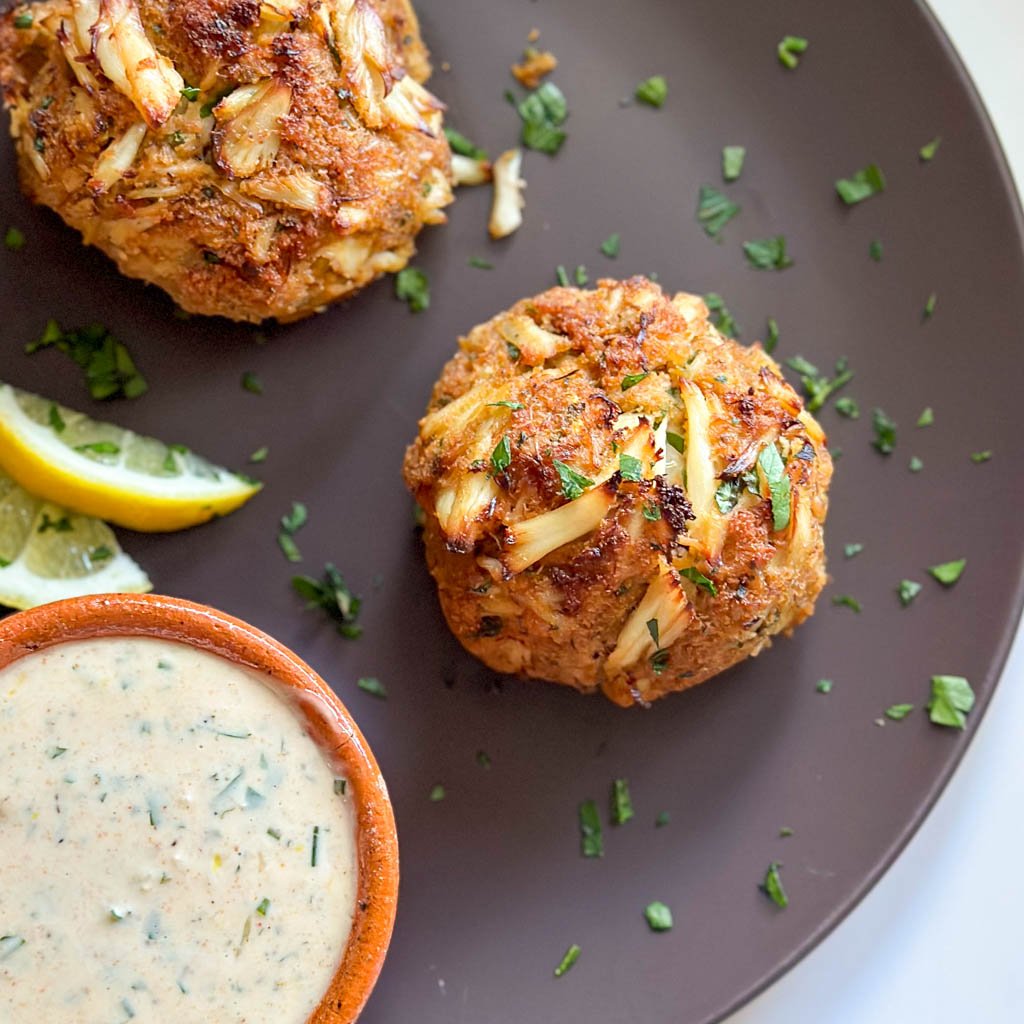 close up view of Maryland crab cakes with aioli sauce in a small saucer