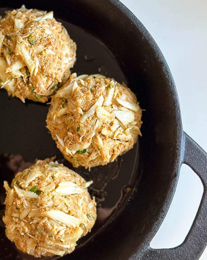 close up view of raw crab cakes in skillet