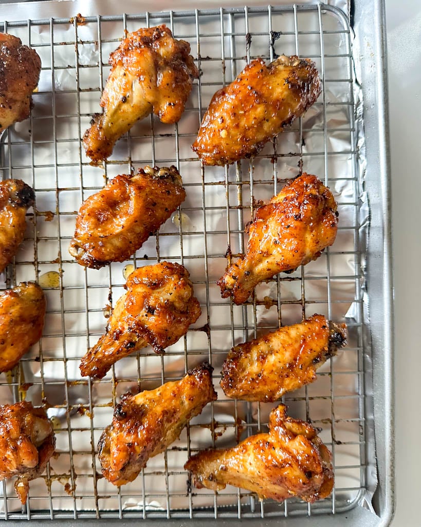 chicken with lemon pepper sauce on a wire racked lined baking sheet tray