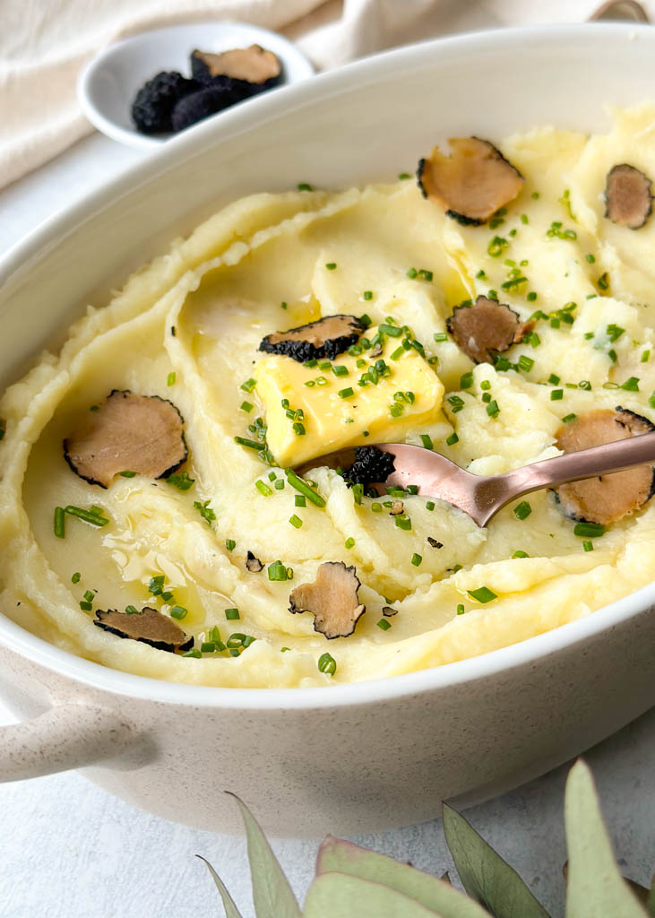 a pot full of truffle mashed potatoes garnished with chives and truffles