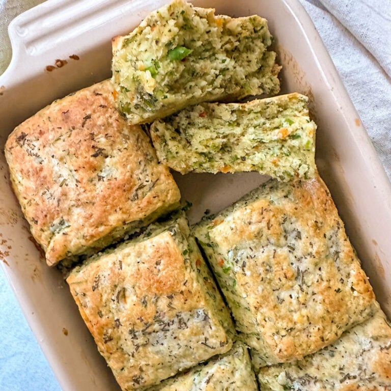 stuffing biscuits in a baking dish with one biscuit split in half to reveal the fluffy, tender center