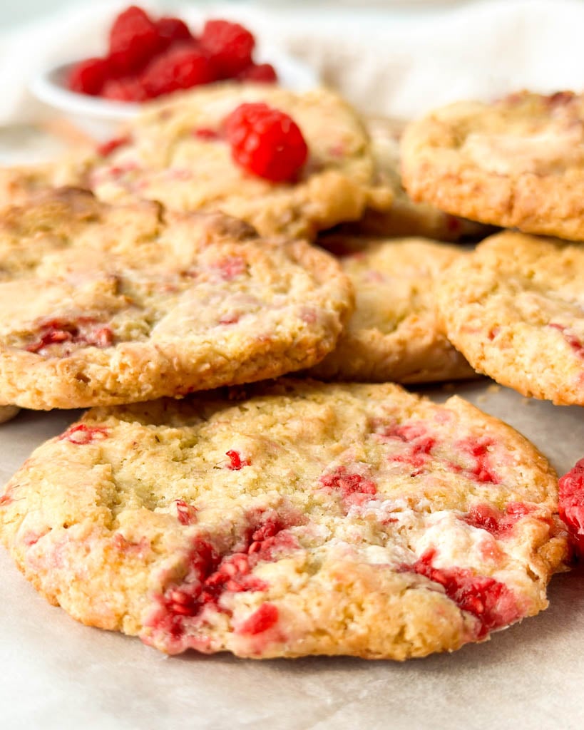 white chocolate raspberry cookies with a small bowl of fresh raspberries in the back