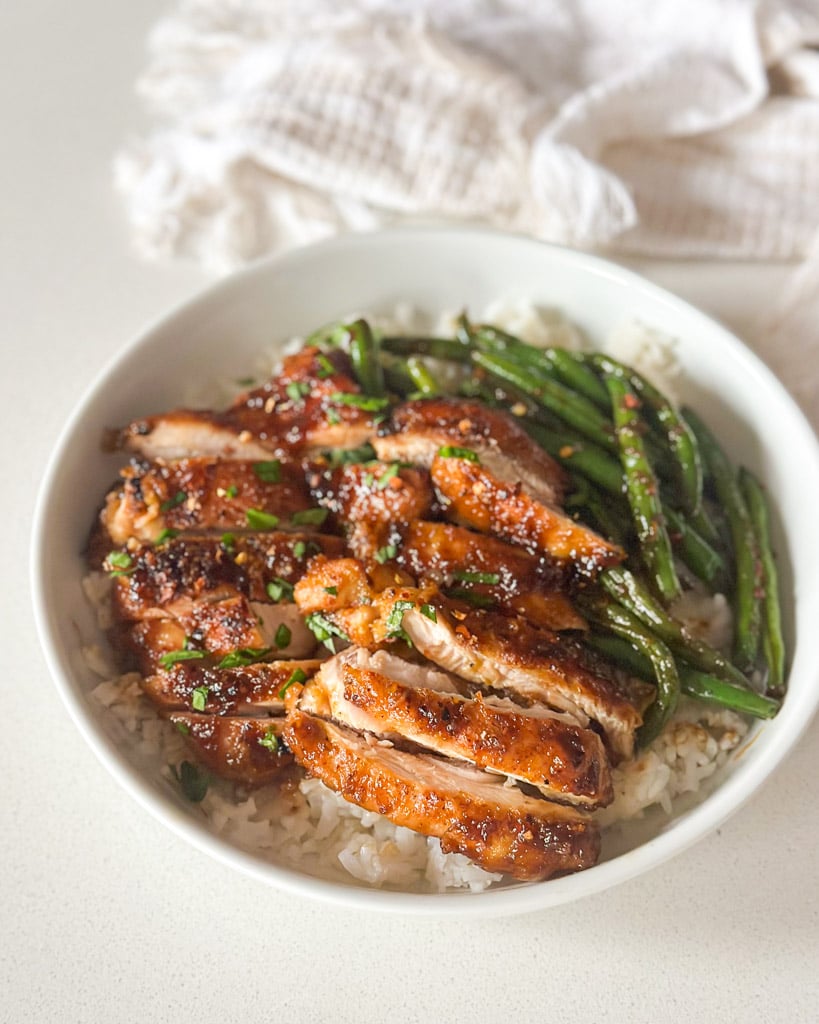 honey ginger chicken served over rice with green beans in a white bowl