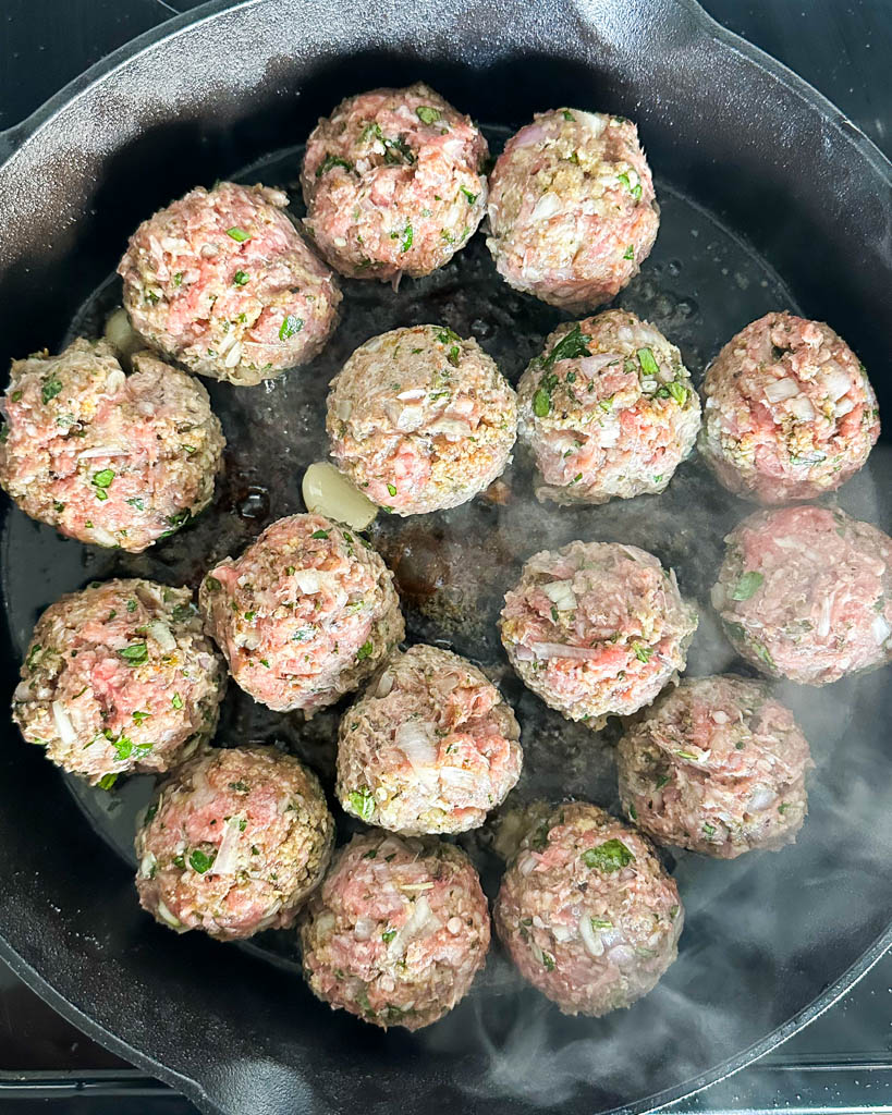 lamb meatballs in a skillet cooking on stove top