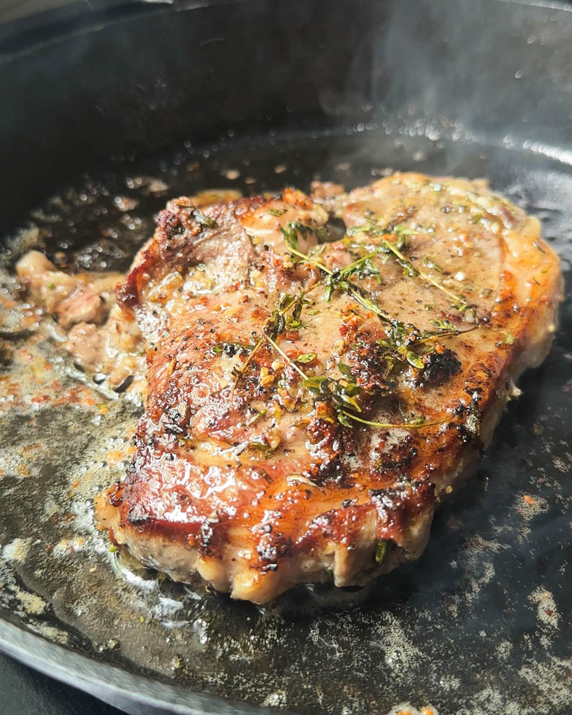 garlic rosemary lamb leg steak in a cast iron skillet with oil and butter