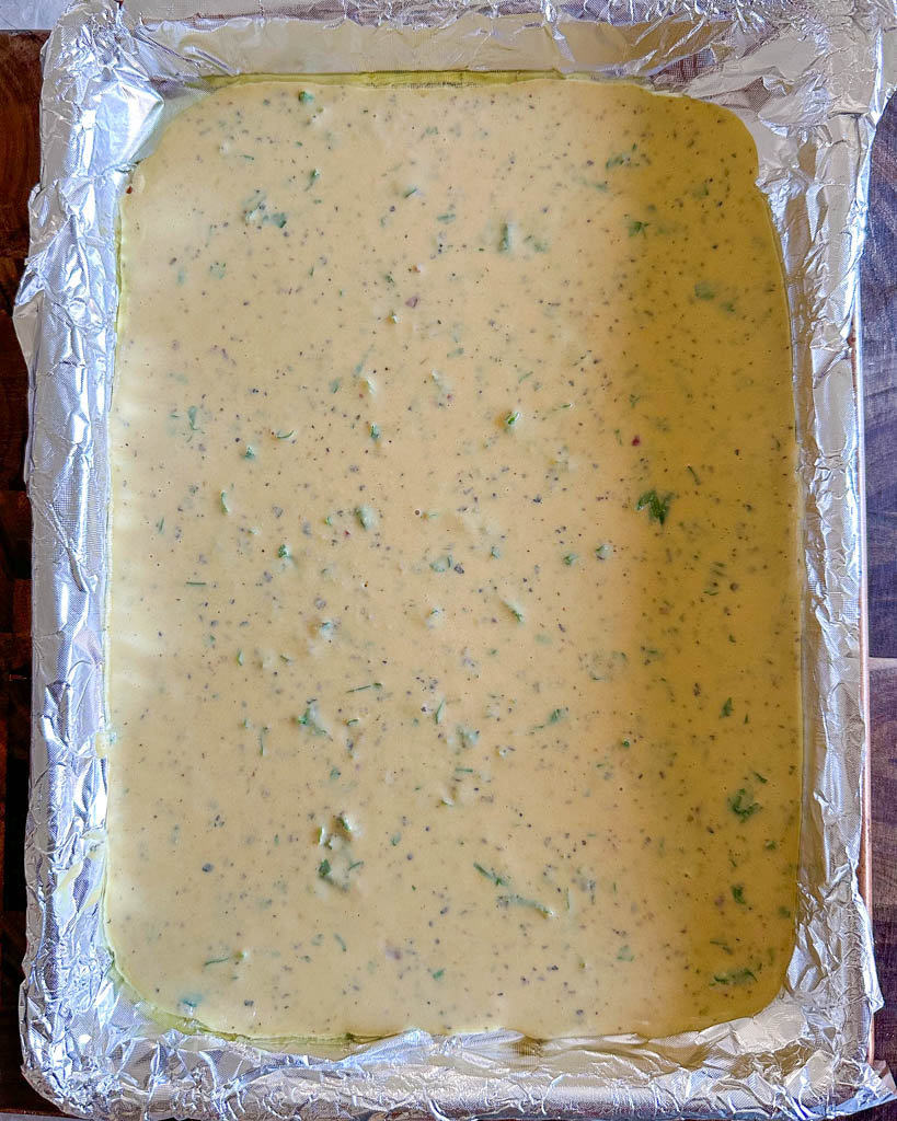 chickpea flatbread mixture in an aluminum foil lined baking tray
