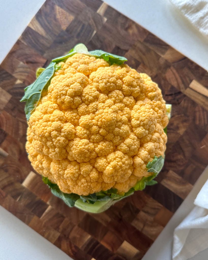 overhead view of a head of cauliflower on a cutting board