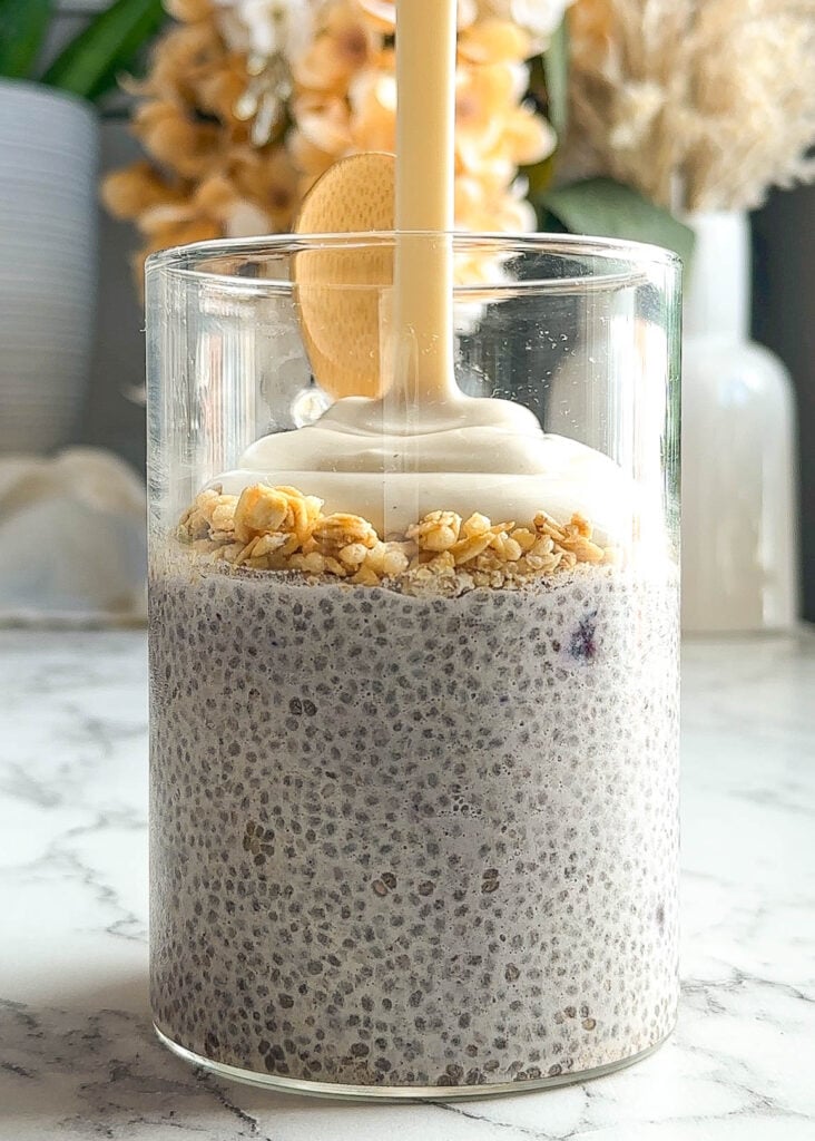 yogurt being poured on a jar full of chia pudding topped with granola