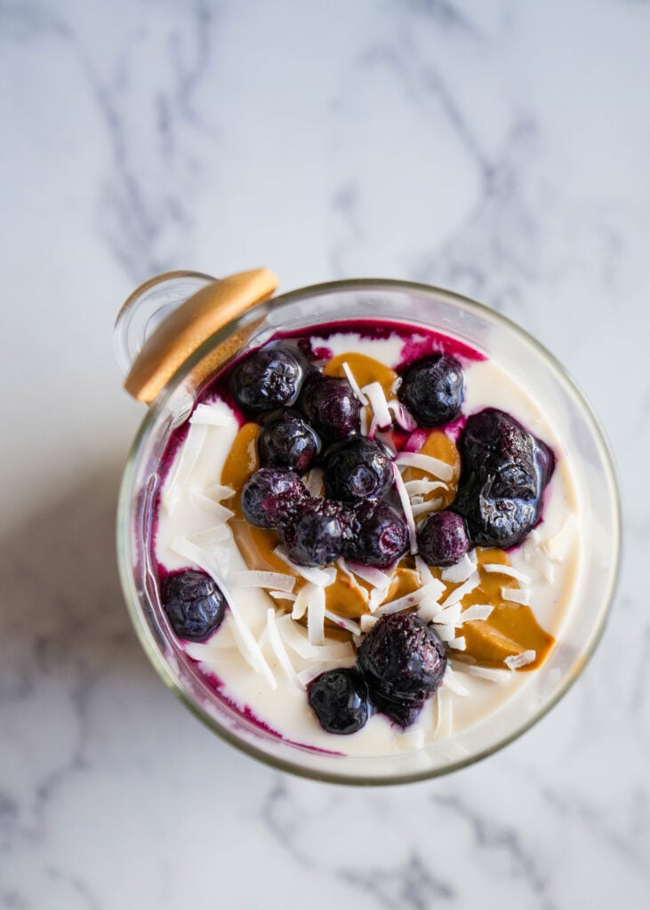 overhead chot of chia pudding topped with blueberries nut butter yogurt and shredded coconut