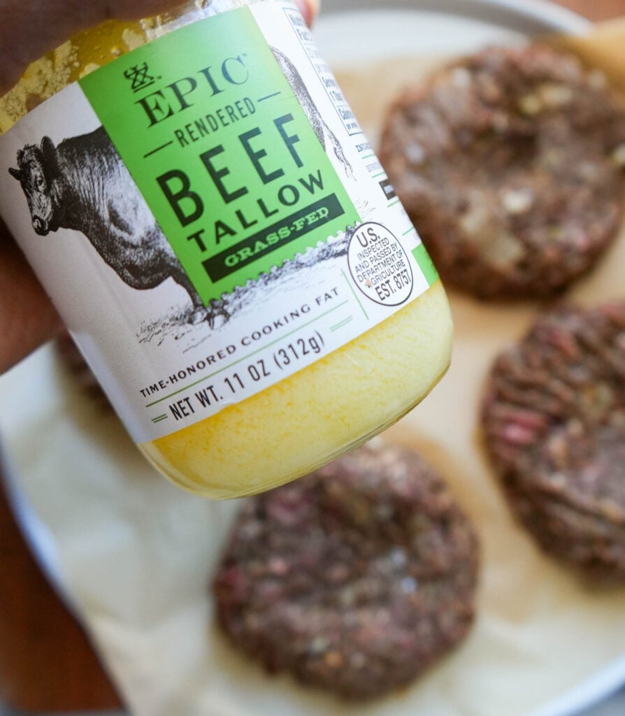 jar of beef tallow close with raw bison patties in the background