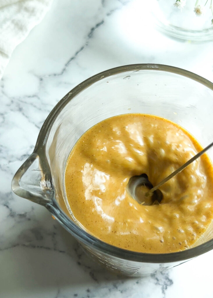 pumpkin flavor cold foam in a measuring cup with milk frother in it